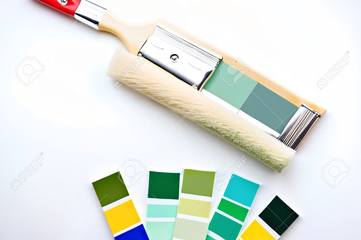 Photo of palette with blue and green colors, roller, brushes