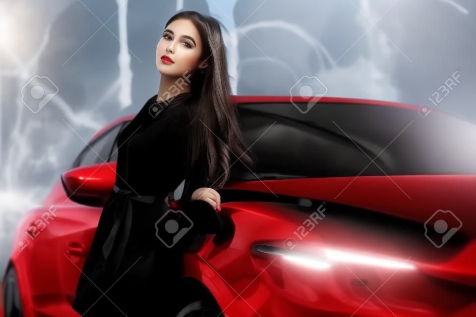 Giovane bella ragazza in abito nero con la vettura sportiva rossa