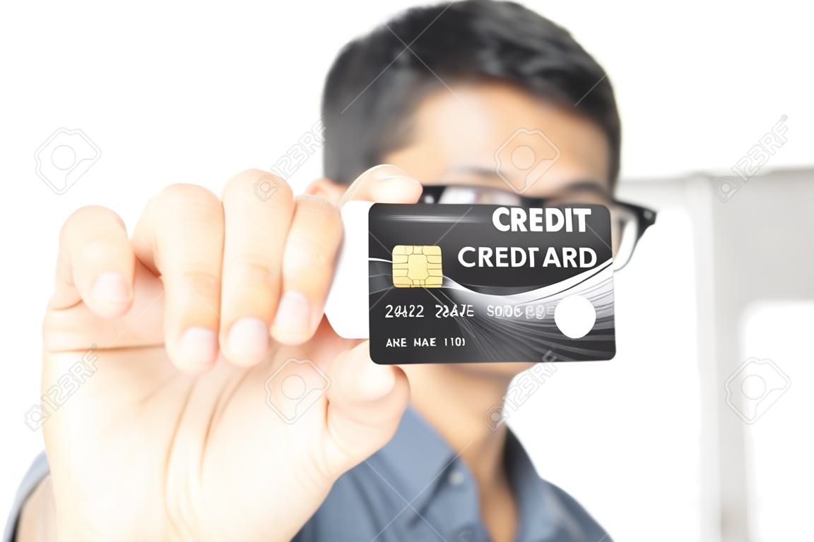 クレジットカードを見せて、白い背景で隔離の正面にそれを伸ばす若い男。