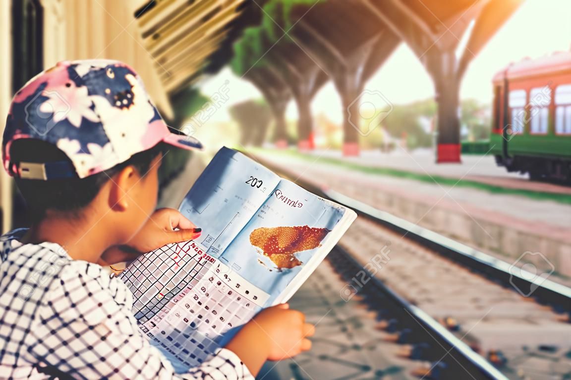 Cute girl in train station waiting to travel. Summer holiday and travel concept.