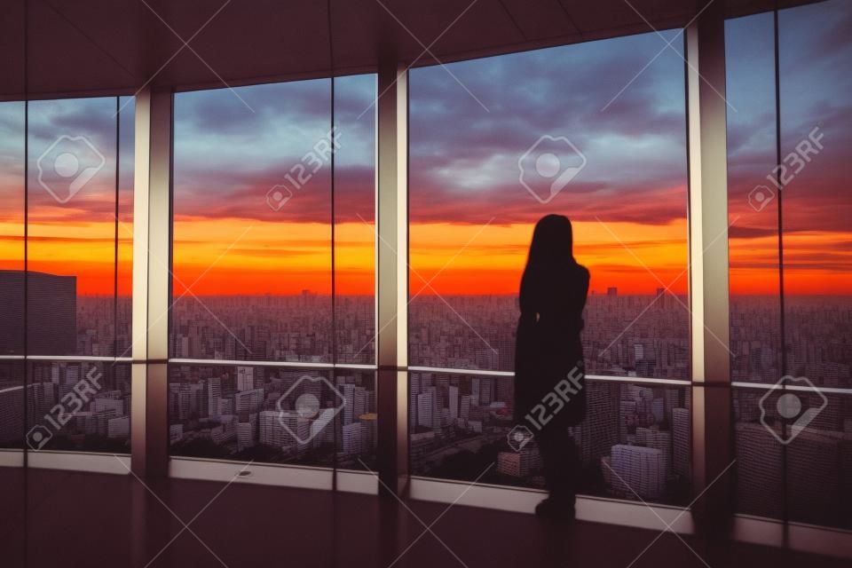 Vue arrière de la femme voyageur regardant Tokyo Skyline et vue sur les gratte-ciel sur le pont d'observation au coucher du soleil au Japon. Ton vintage