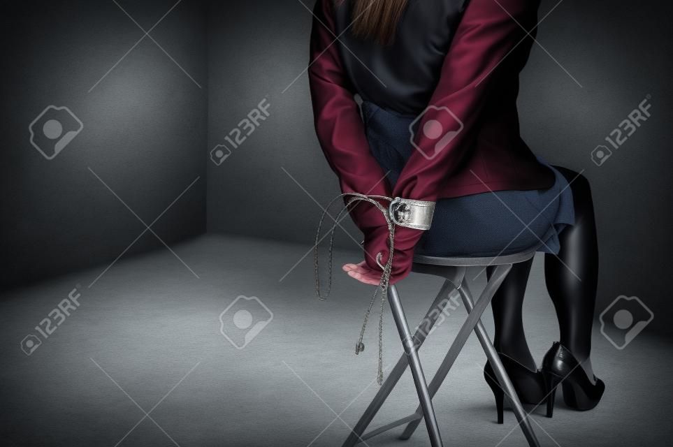 여자 손 바인딩. 여성들은 수갑을 채우고 의자에 앉아 있었습니다. 여성은 손을 의자에 묶었습니다. 범죄 개념입니다. 범죄 개념입니다. 보세 사업.