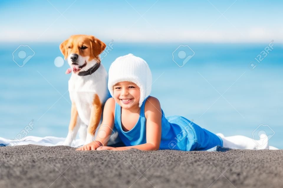 Heureux garçon jouant avec son chien au bord de la mer contre le ciel bleu. les meilleurs amis s'amusent en vacances. photo de haute qualité.