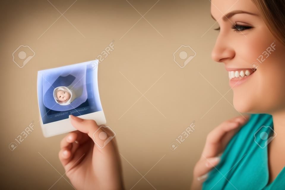Retrato de joven mujer embarazada feliz celebración de una ecografía de su hijo nonato.