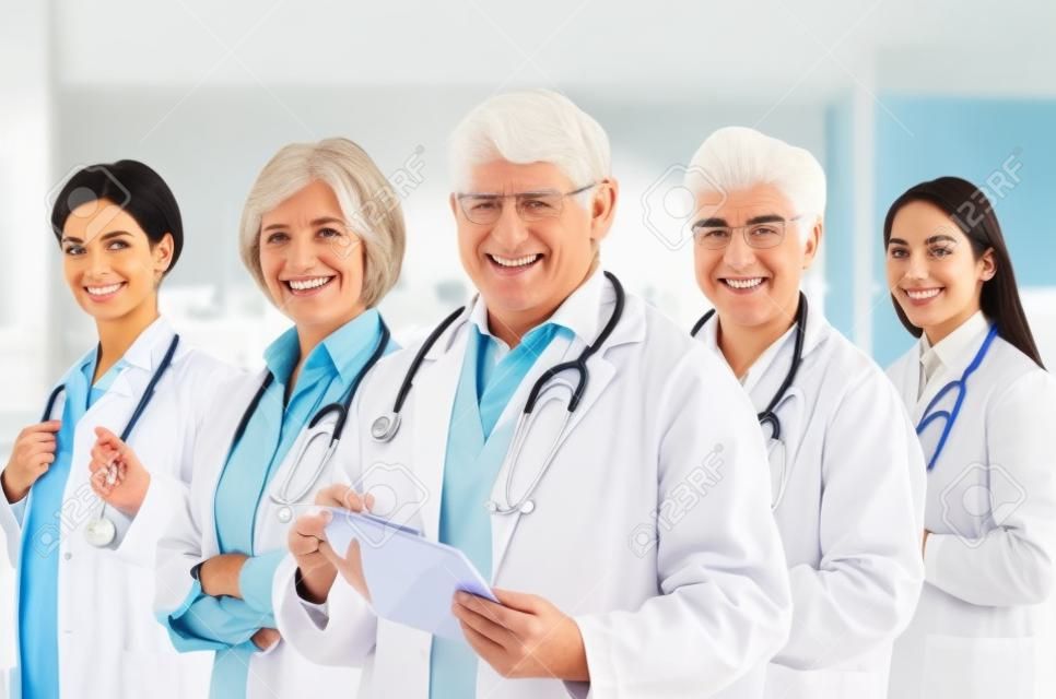 Equipo de profesionales de la medicina de plomo por alto médico de pelo blanco mirando a cámara, sonriendo.