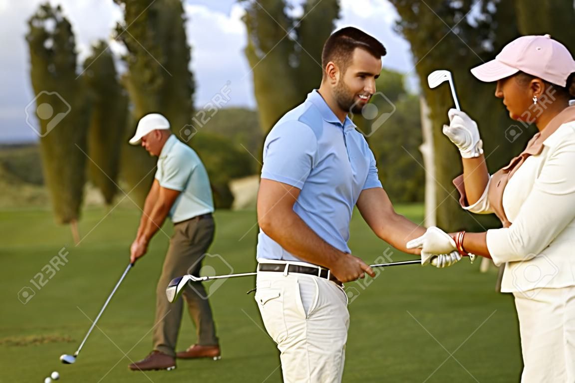 Vrouwelijke golfer leren golfen, mannelijke instructeur helpen.