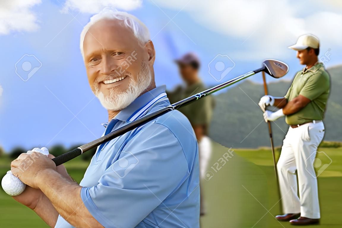 Closeup portrait of mature male golfer holding golf club, smiling happy, looking at camera.�