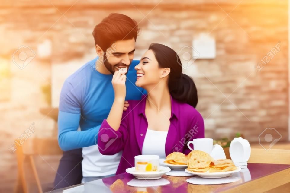 Heureux couple romantique ayant le petit déjeuner ensemble, se nourrissant les uns des autres.
