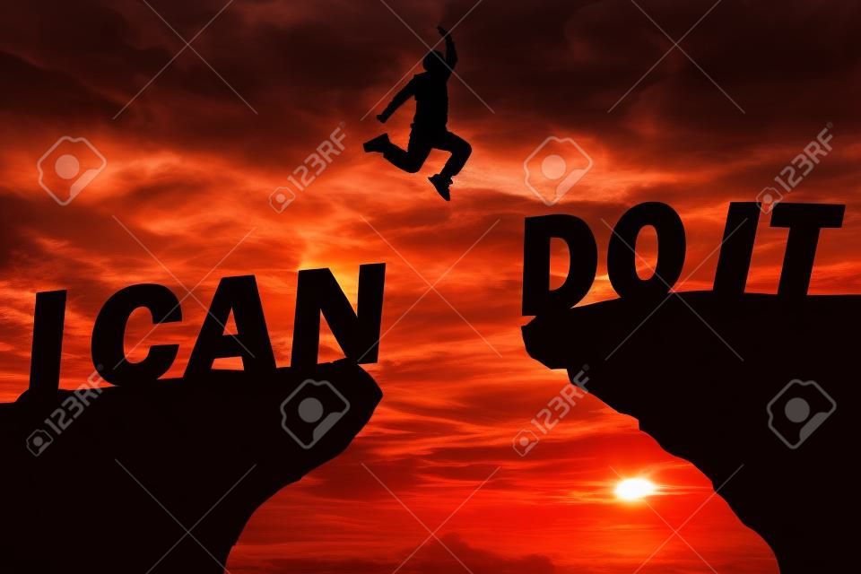 Silhouette sunset background.A man are jumping over to cliff and jump  between"i can do it "word. This photo shows about freedom , Active and successful,Photo Silhouette and active concept idea.