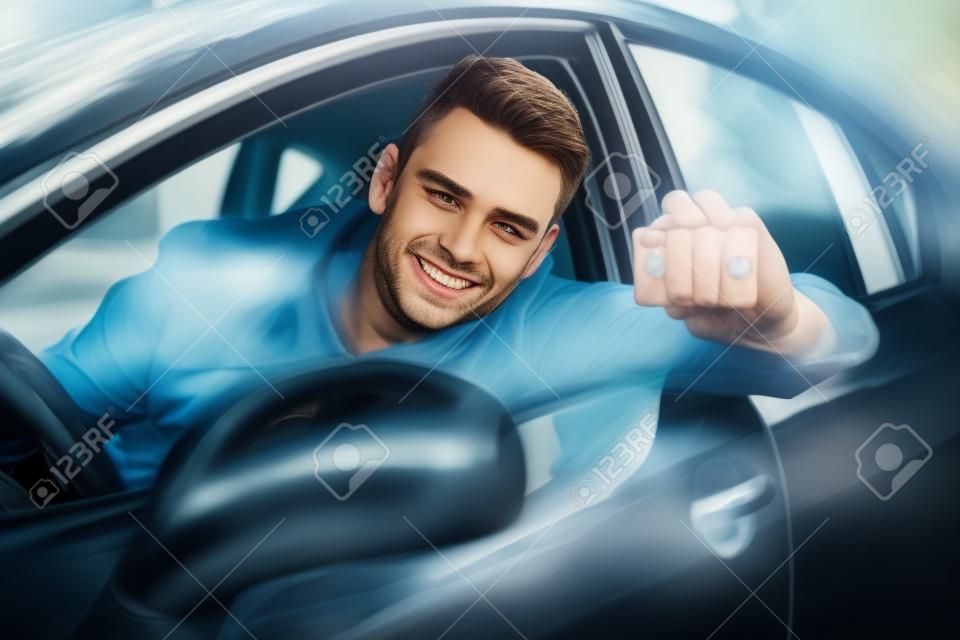 Portret van een knappe jongeman met een auto
