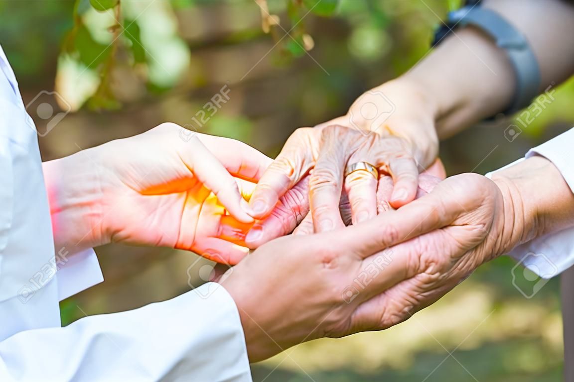 Close up medical doctor holding elderly female's trembling hands