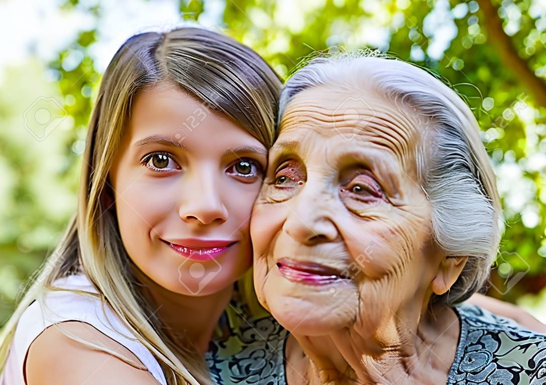 Close up picture of senior disabled woman with loving granddaughter in the garden