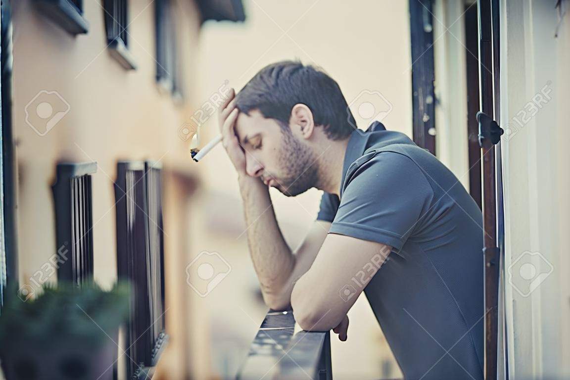 joven solo fuera en la casa balcón terraza fumando deprimido, destruido, perdido y triste sufrir crisis emocional y depresión