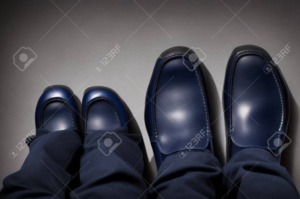 Zapatos en las piernas de un padre y su hijo