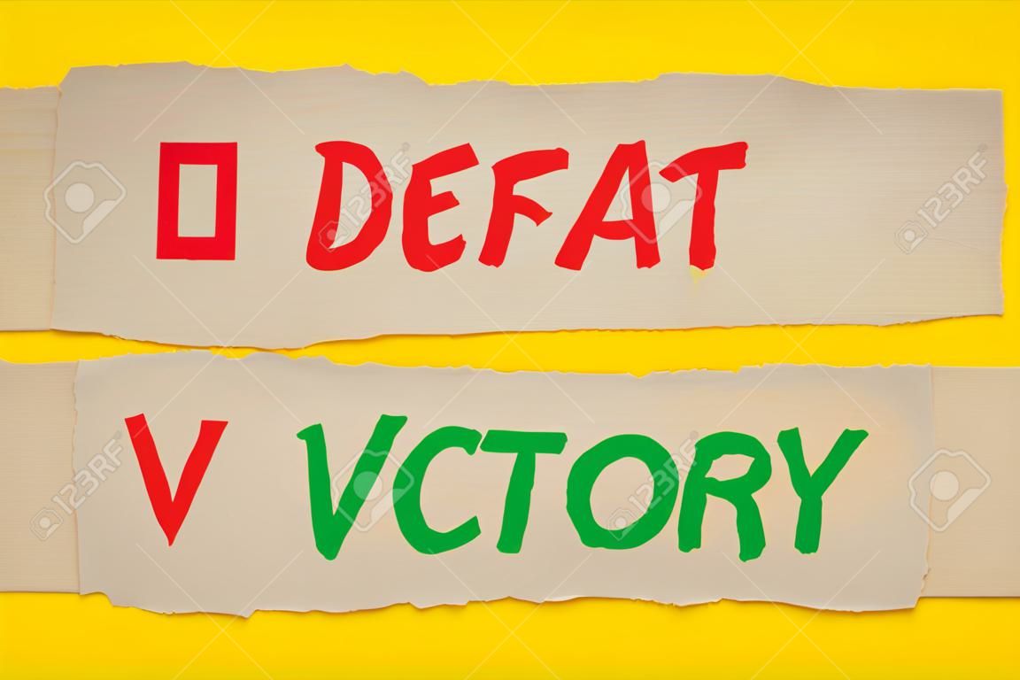 Defeat vs Victory words written on old paper on yellow background.