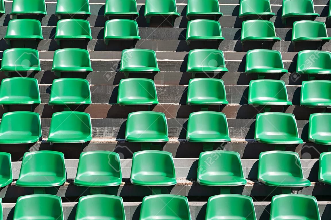 Afbeelding van groene plastic stadion stoelen in rijen. De stoelen zijn gevuld het frame als achtergrond. Dit is een dag opname van een leeg stadion.