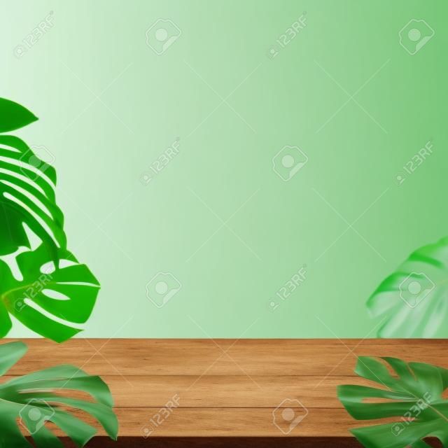 Mesa de madera con hojas verdes de monstera borrosas como marco sobre fondo blanco
