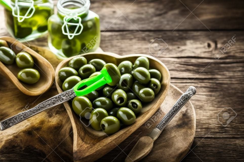 Groene olijven liggen op tafel in een kom met olijfbomen. Het concept van gezond eten.