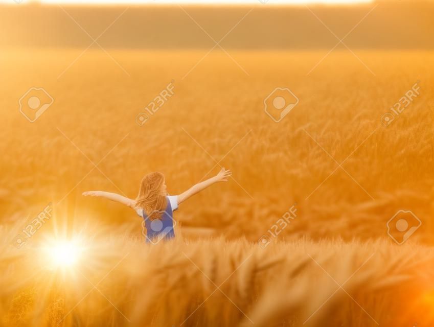 Девушка насладиться с солнцем в поле пшеницы