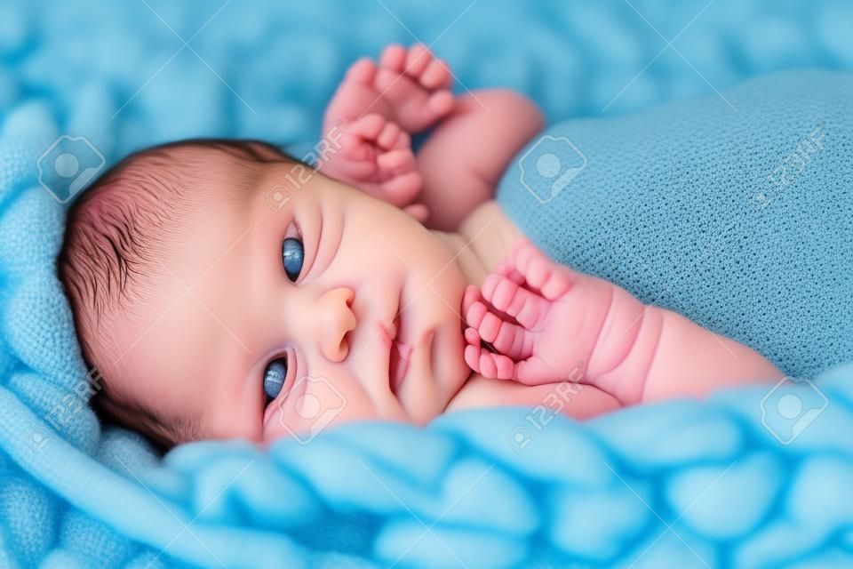Il neonato sulla coperta di crochet giganti blu cerca