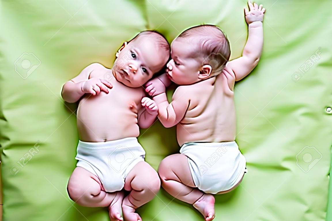 グリーンの上に横たわる面白い双子の兄弟の赤ちゃん