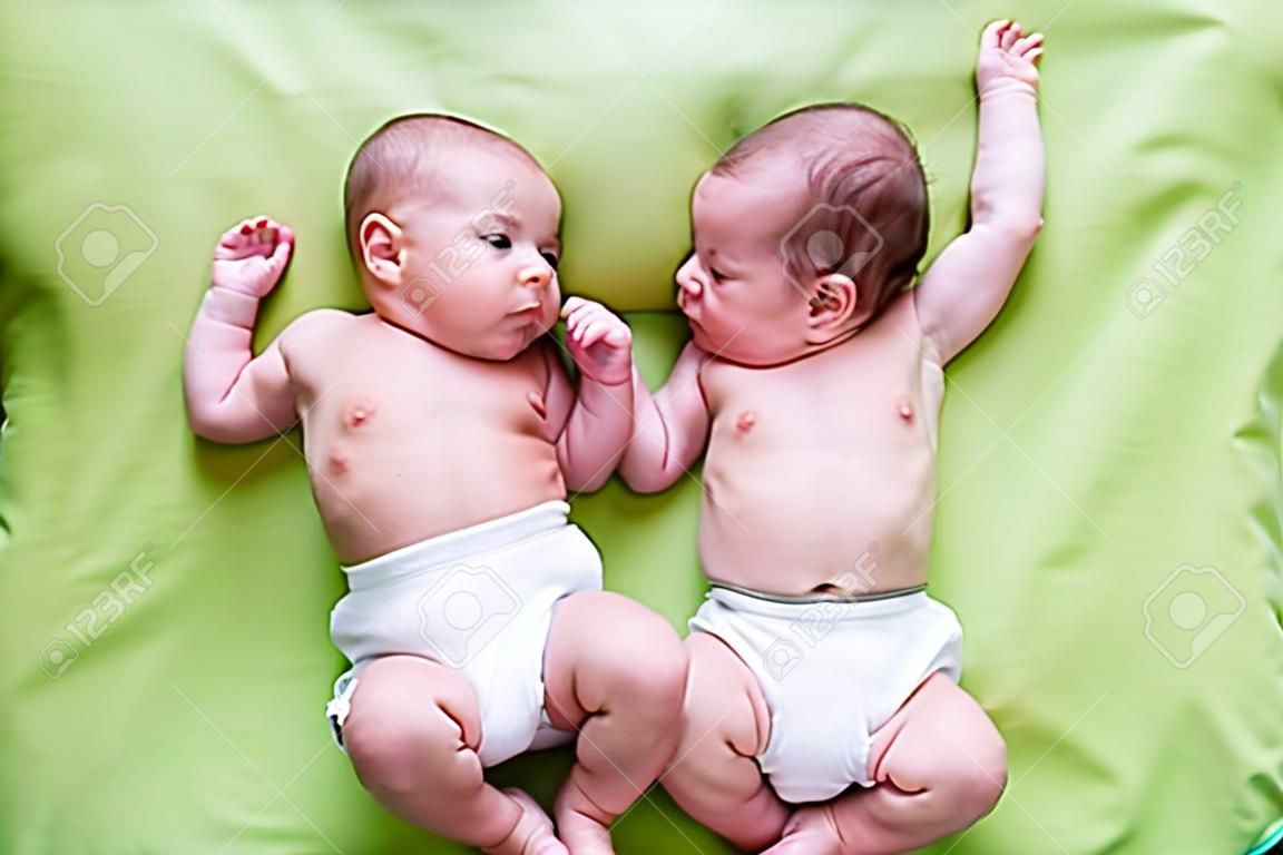 グリーンの上に横たわる面白い双子の兄弟の赤ちゃん