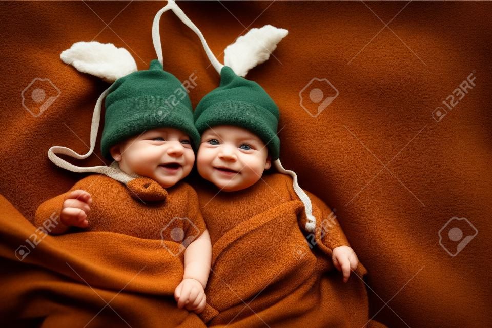 Dois irmãos gêmeos bebês vestidos com chapéus de bolota