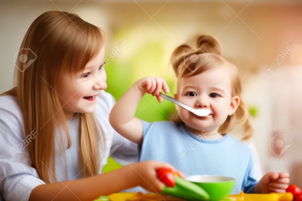 ребенок девочка ест с ложкой в ​​помещении при кухне