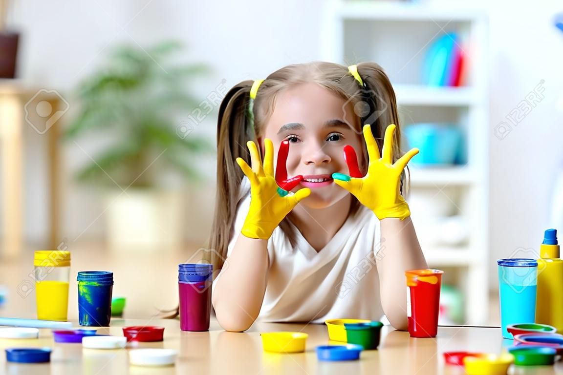 schattig vrolijk meisje toont haar handen geschilderd in heldere kleuren