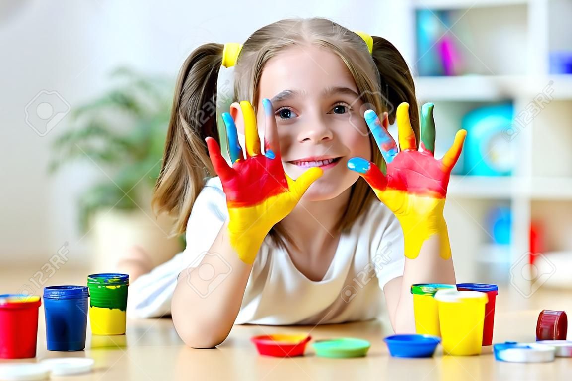 schattig vrolijk meisje toont haar handen geschilderd in heldere kleuren