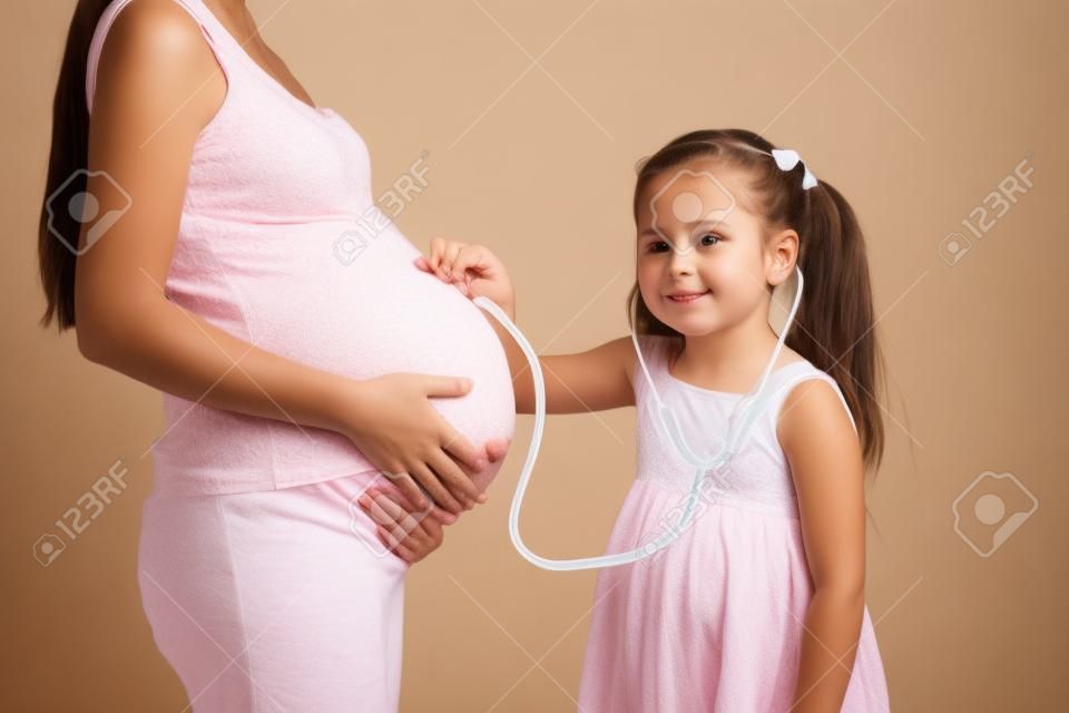 kid girl listening to pregnant mom tummy isolated
