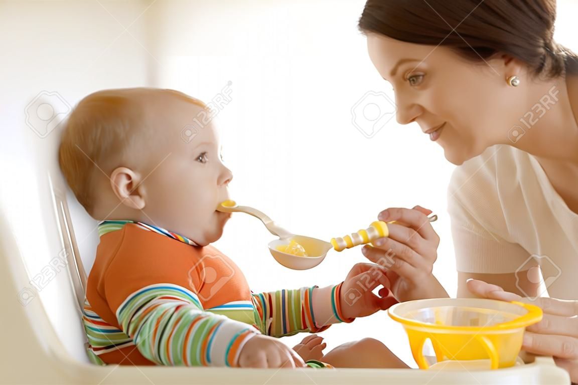 Mother spoon-feeding her child boy