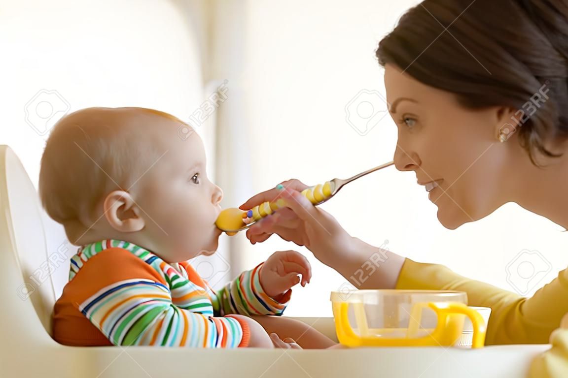 Mother spoon-feeding her child boy