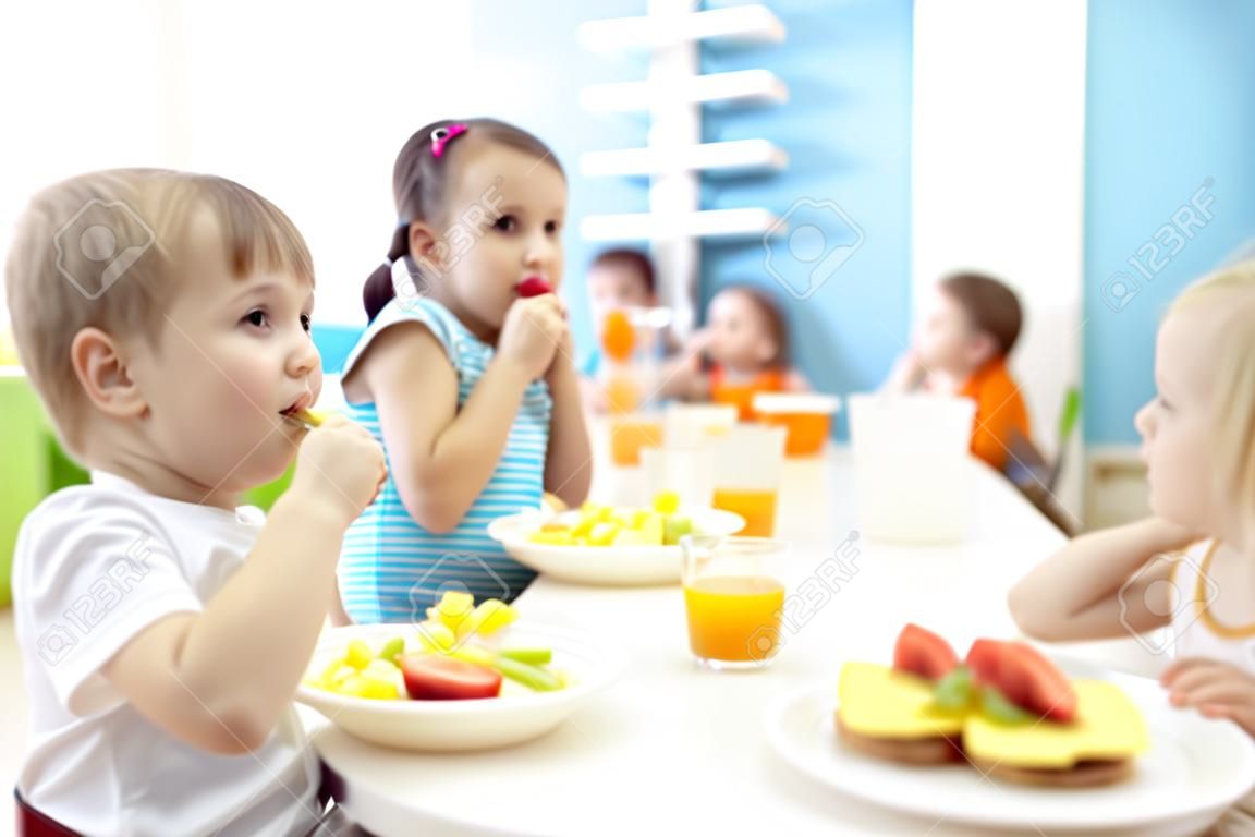 Kids have a lunch in daycare centre. Children eating healthy food in kindergarten