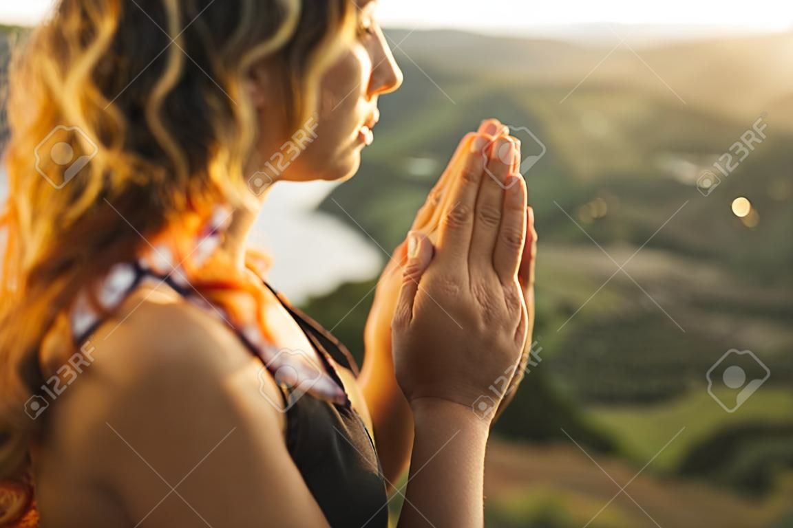 Woman praying alone at sunrise. Nature background. Spiritual and emotional concept. Sensitivity to nature