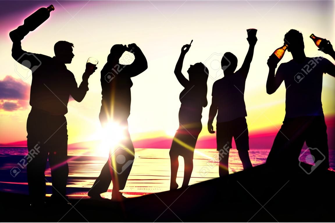Menschen (zwei Paare) am Strand feiern, trinken und haben viel Spaß im Sonnenuntergang (nur die Silhouette der Menschen ist zu sehen, Menschen haben Flaschen in den Händen, durch die die Sonne scheint)