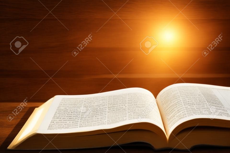 Sacra Bibbia con taccuino e matita su tavola di legno contro la luce del sole mattutino per la devozione cristiana, spazio copia