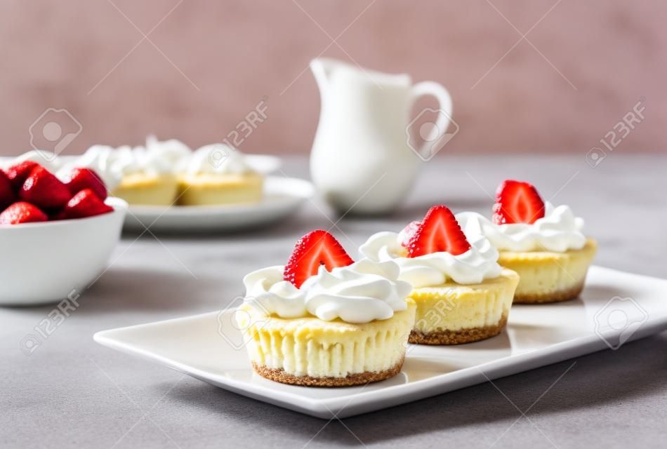 迷你芝士蛋糕配草莓和奶油在盤子上