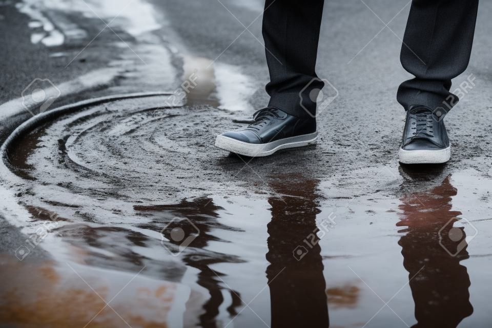 the man stops with his foot in a puddle