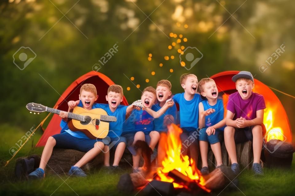 enfants heureux en chantant des chansons autour du feu de camp