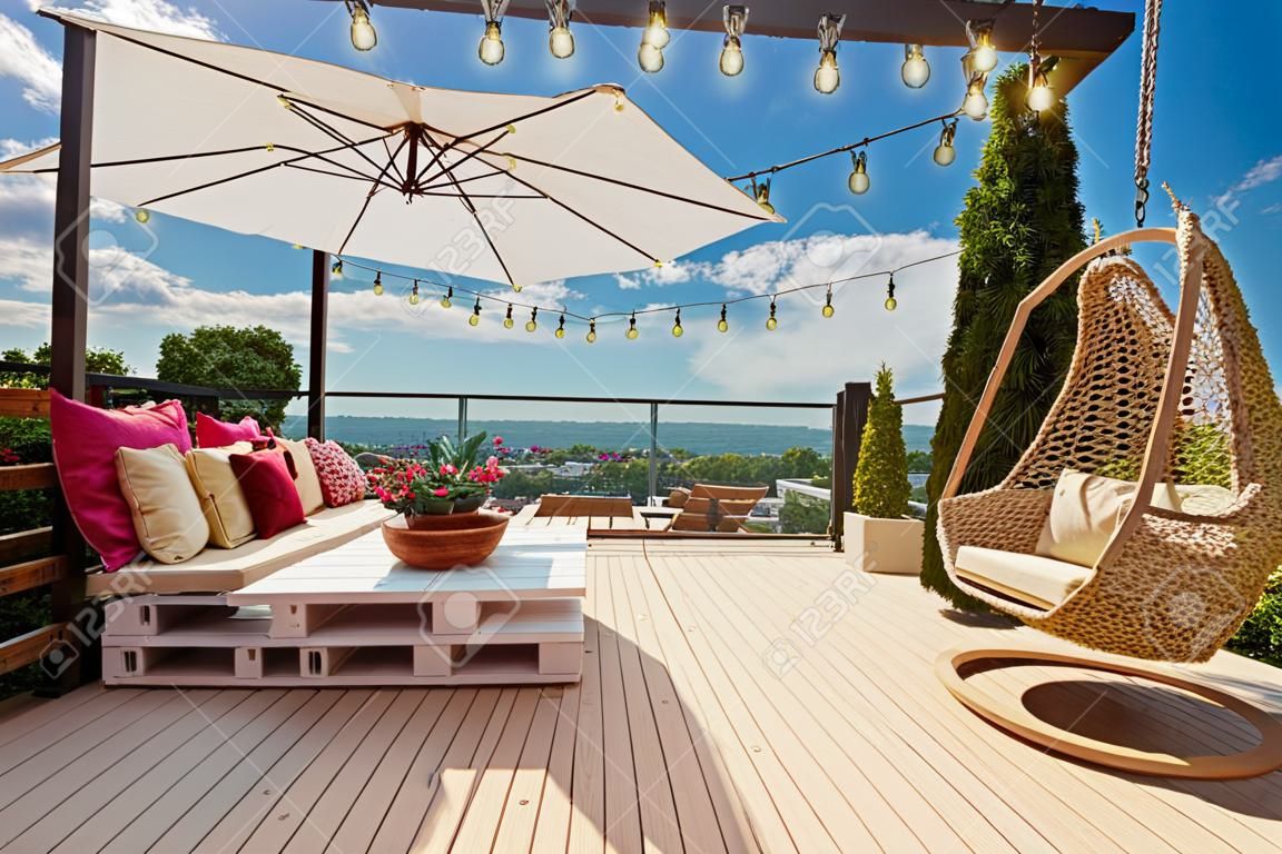 un confortable patio sur le toit avec des meubles de palettes en bois et une balançoire suspendue aux beaux jours d'été
