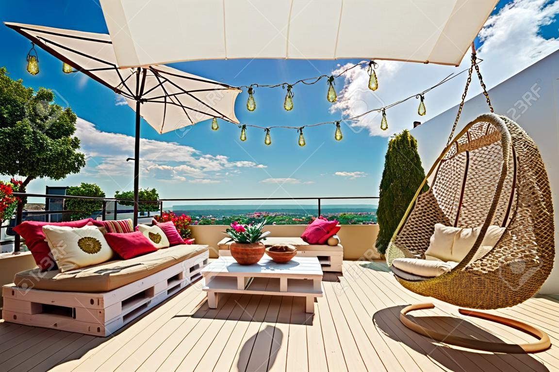 un confortable patio sur le toit avec des meubles de palettes en bois et une balançoire suspendue aux beaux jours d'été