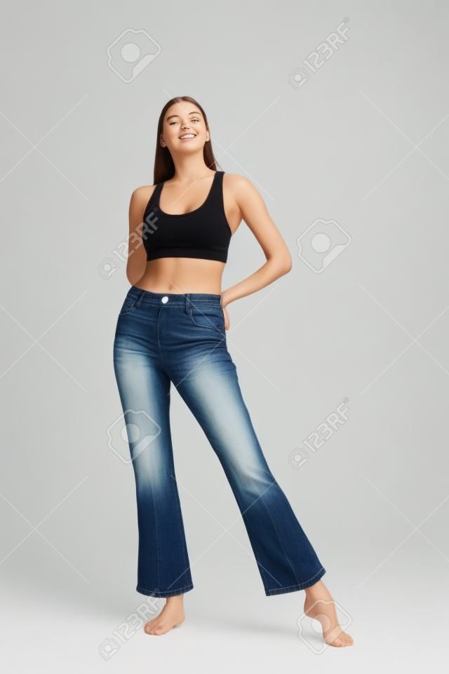 Girl in jeans and barefoot posing on a white background