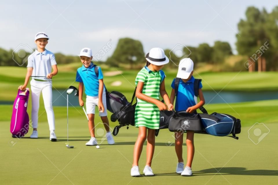 Niños caminando en espacio abierto con bolsas en la escuela de golf