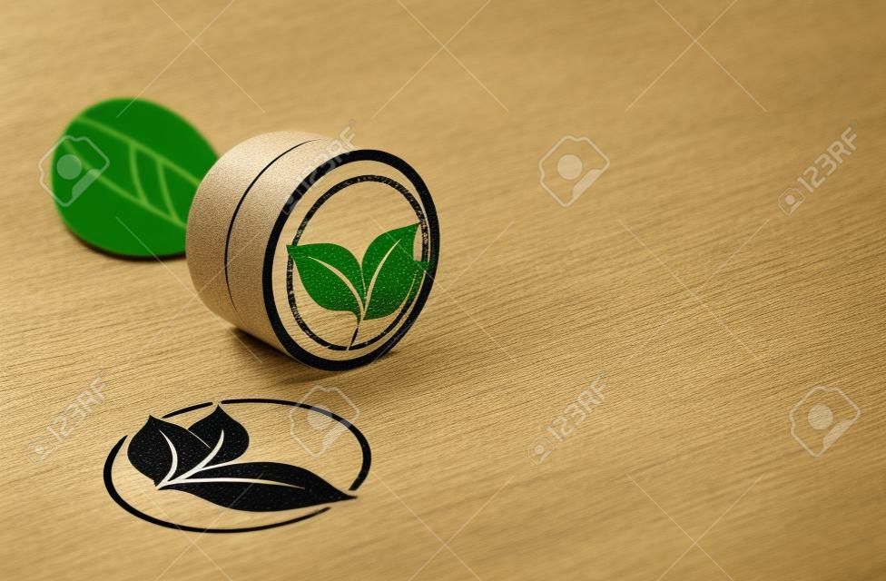 Rubber stamp over paper background with leaves symbol printed on it. Concept image for eco friendly communication.