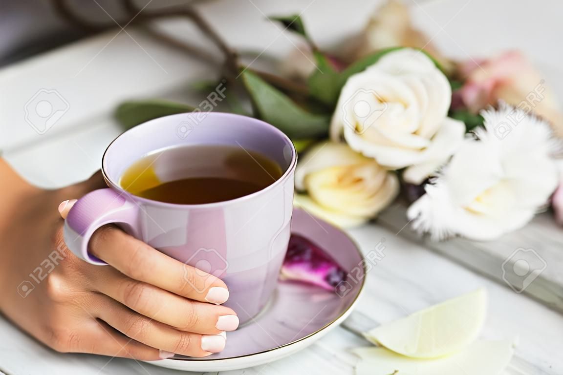 Frau, die heiße Tasse Tee auf einem hölzernen Hintergrund anhält. Morgen, Getränk, Pause