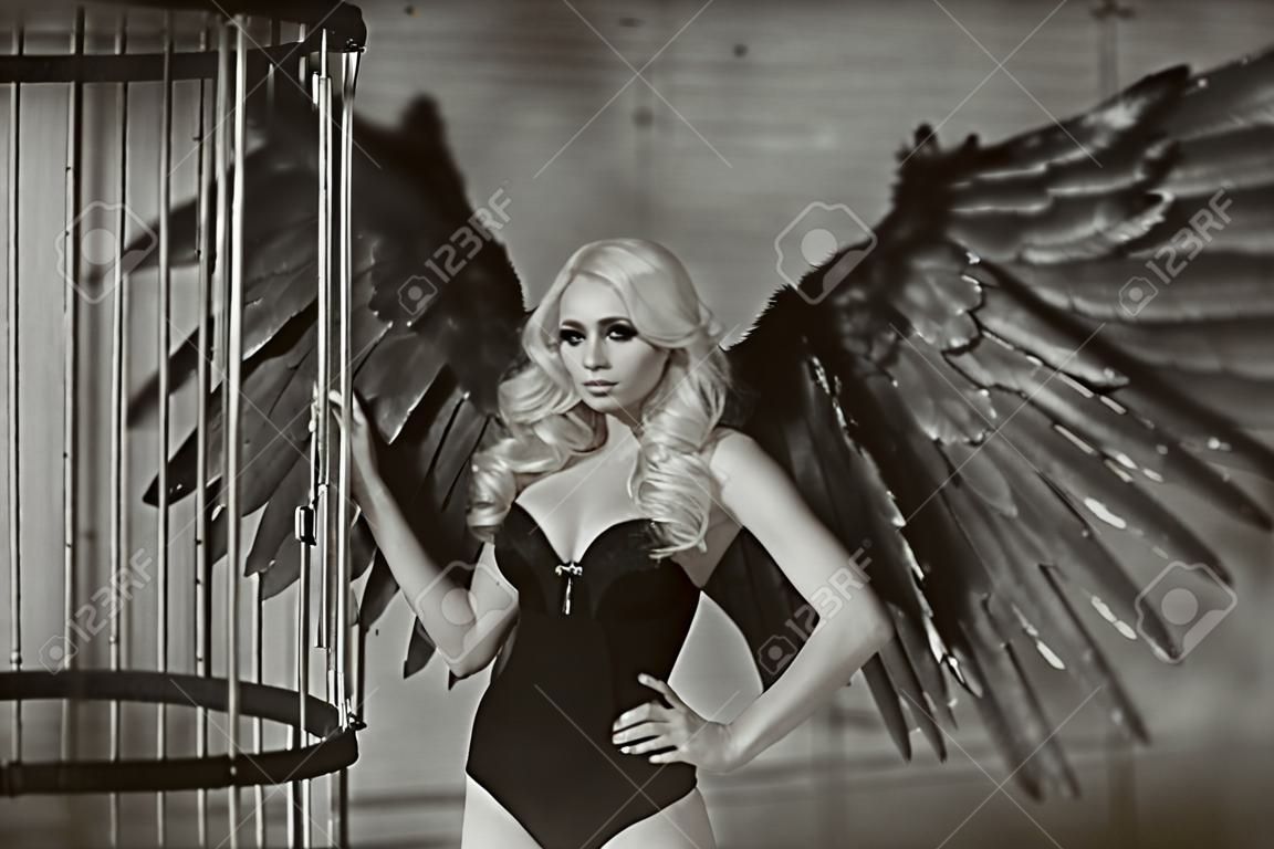 blonde Frau mit schwarzen Flügeln in einem Käfig. Engel, Mystizismus