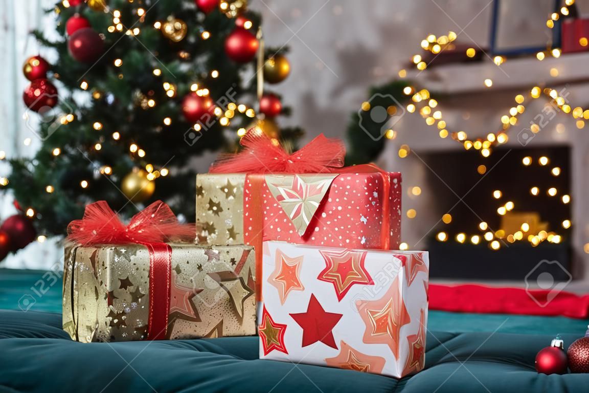 Decorated room with fir tree with red and golden ball ornaments, light garlands, gift boxes for Christmas and New year holidays