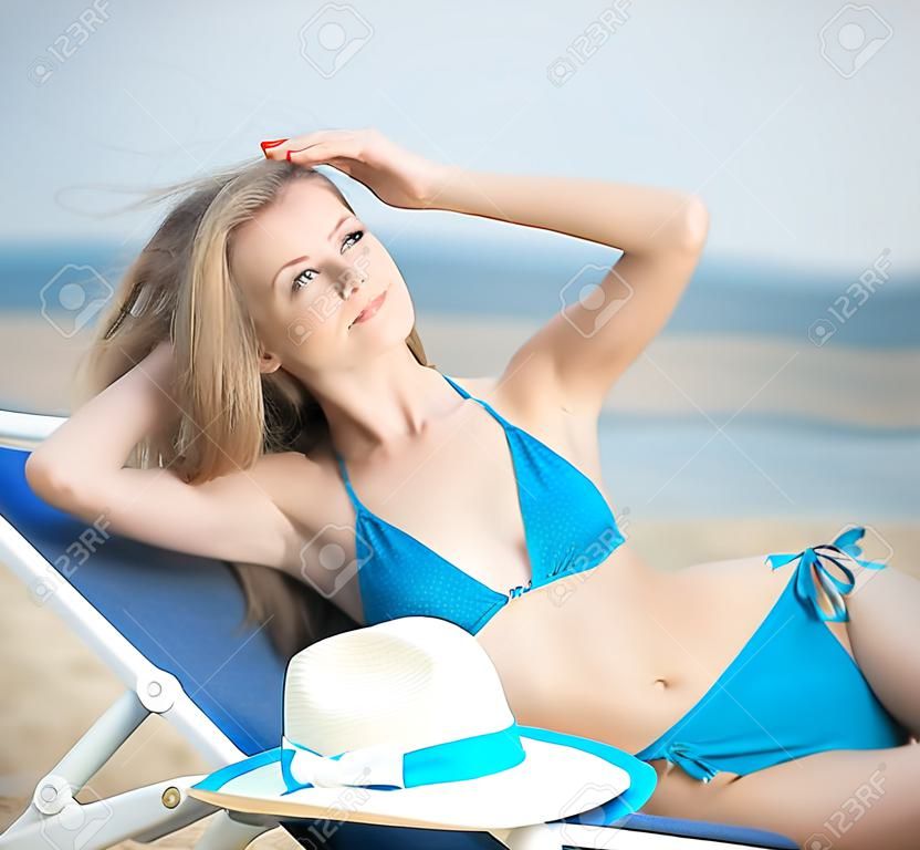 Young lady sunbathing on a beach. Beautiful woman posing at the