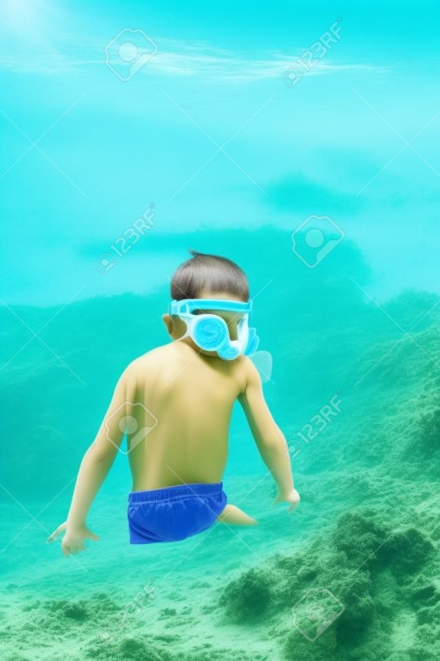 Carino piccolo bambino che indossa la maschera e pinne per le immersioni in spiaggia di sabbia tropicale.